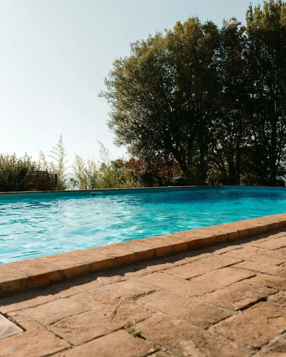 Piscina con bordo in cotto in un giardino toscano
