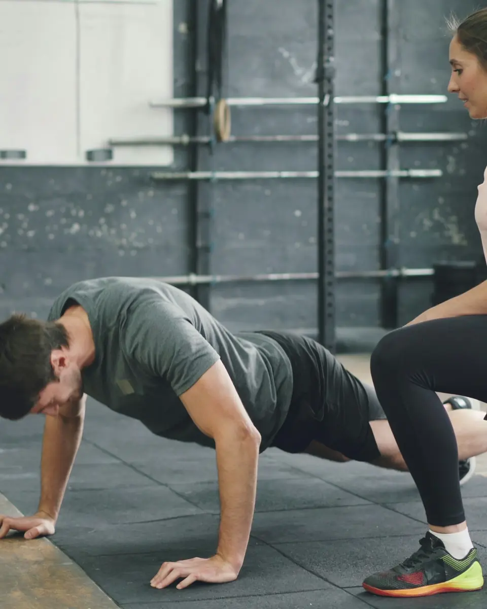 Personal trainer che segue un cliente in palestra